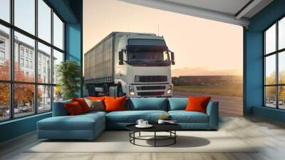 Front-View of Semi-Truck with Cargo Trailer Driving on a Highway. He's Speeding Through Industrial Warehouse Area with Sunset in the Background. Wall mural