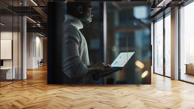 Handsome Black African American Male is Standing in Meeting Room Behind Glass Walls with Laptop Computer in an Creative Agency. Project Manager Wearing White Jumper and Working on App User Interface. Wall mural