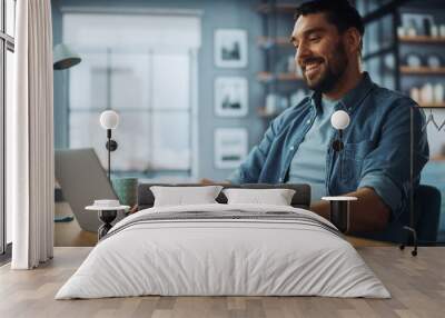 Handsome Caucasian Man Working on Laptop Computer while Sitting on a Sofa Couch in Stylish Cozy Living Room. Freelancer Working From Home. Browsing Internet, Using Social Networks, Having Fun. Wall mural