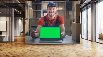 Happy Worker Points at Laptop, Shows Thumbs Up and Notebook with Green Mock-up Screen Display.  Wall mural