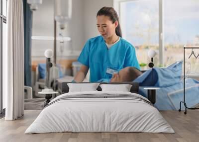 Hospital Ward: Friendly Chinese Head Nurse Connects Finger Heart Rate Monitor / Pulse oximeter to Male Patient Resting in Bed. Nurse Checks Man Getting well after Surgery. Wall mural