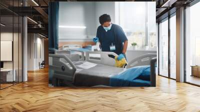 Hospital Ward: Professional Black Nurse Wearing Face Mask, Wiping the Bed, Cleaning Room After Covid-19 Patients Recover. Disinfection, Sterilizing, Sanitizing Clinic after Coronavirus Infected People Wall mural