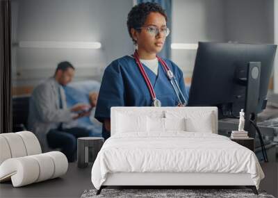 hospital ward: professional smiling black female head nurse or doctor wearing stethoscope uses medic Wall mural