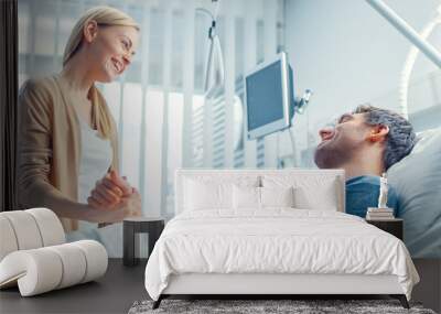 In the Hospital, Happy Wife Visits Her Recovering Husband who is Lying on the Bed. They Holding Hands and Smile. Wall mural