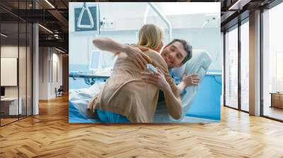 In the Hospital, Happy Wife Visits Her Recovering Husband who is Lying on the Bed. They Lovingly Embrace and Smile. Wall mural