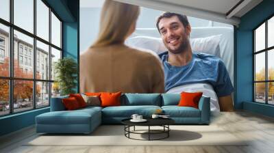 In the Hospital, Man Recovering from Illness Lying in Bed, Loving Wife Visits Him. He is Smiling and Looking at Wife. Wall mural