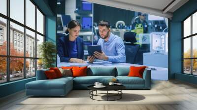 Industry 4.0 Modern Factory Meeting Room: Chief Engineer Holds Digital Tablet Computer, Shows it to Female Specialist, They Have Discussion. Design Electronic Machinery With Futuristic Design Wall mural