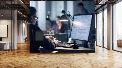 Late at Night in the Office. Design Engineer Works on His Personal Computer. On His Display We See Blueprints. Office Looks Modern. In the Background People Working. Wall mural