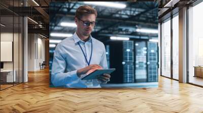 Male Engineer Programs Something while Holding Tablet Computer in His Hands. He Works in a Dark Modern High-Tech Office. High-Speed Data Transfer and Smooth Server Operation, Analytics Wall mural