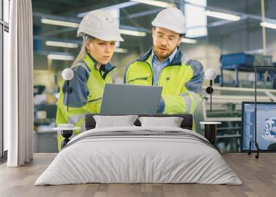 Male Industrial Worker and Female Chief Mechanical Engineer in Walk Through Manufacturing Plant while Discuss Factory's New Project and Using Laptop. Facility Has Working Machinery. Wall mural