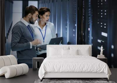 Male IT Specialist Holds Laptop and Discusses Work with Female Server Technician. They're Standing in Data Center, Rack Server Cabinet is Open. Wall mural