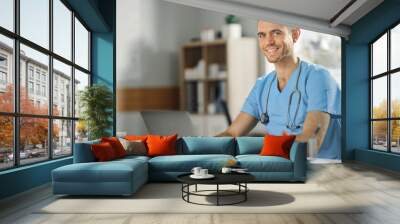 Male Nurse Wearing Blue Uniform Working on Laptop Computer at Doctor's Office and Smiling on Camera. Health Care Professional Working On Battling Stereotypes to Gender Diversity in Nursing Career. Wall mural