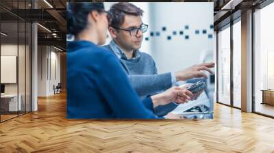 Modern Factory: Male Industrial Engineer Explains to Female Project Supervisor Functions of the Machine Part Comparing it to one on Computer Screen. They use CAD Software for Design, Development Wall mural