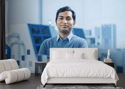 Modern Factory Office: Portrait of Handsome Indian Engineer Crosses Arms and Smiles Charmingly. In the Background High Tech Facility with CNC Machinery, Robot Arm and People Working Wall mural