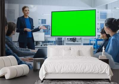 Modern Industrial Factory Meeting: Confident Female Engineer Uses Interactive Green Mock-up Screen Whiteboard, Makes Report to a Group of Engineers, Managers  Wall mural