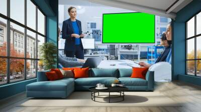 Modern Industrial Factory Meeting: Confident Female Engineer Uses Interactive Green Mock-up Screen Whiteboard, Makes Report to a Group of Engineers, Managers  Wall mural