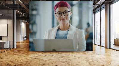 Modern Office: Portrait of Beautiful Authentic Specialist with Short Pink Hair Standing, Holding Laptop Computer, Looking at Camera, Smiling Charmingly. Working on Design, Data Analysis, Plan Strategy Wall mural