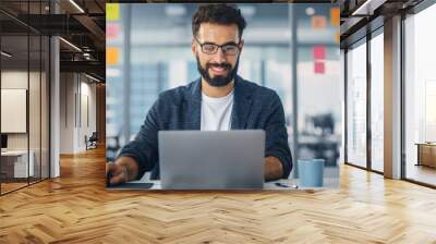 Modern Office: Portrait of Young Stylish Businessman Wearing Glasses Works on Laptop, Does Data Analysis, Website Design, Creative Developemnt. Digital Entrepreneur Works on e-Commerce Startup Project Wall mural