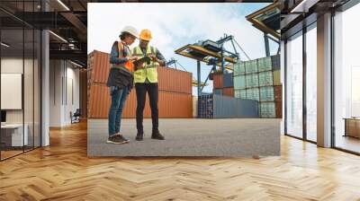 Multiethnic Female Industrial Engineer with Tablet and Black African American Male Supervisor in Hard Hats and Safety Vests Stand in Container Terminal. Colleagues Talk About Logistics Operations. Wall mural