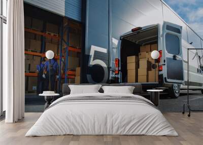 Outside of Logistics Distributions Warehouse: Two Workers Load Delivery Truck with Cardboard Boxes, Drive Off to Deliver Online Orders, Purchases, E-Commerce Goods. Wall mural