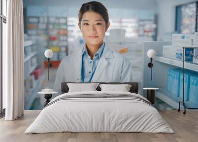 Pharmacy Drugstore: Portrait of Beautiful Asian Pharmacist Uses Digital Tablet Computer, Looks at Camera and Smiles Charmingly, Behind Her Shelves Full of Medicine Packages. Medium Close-up Shot Wall mural