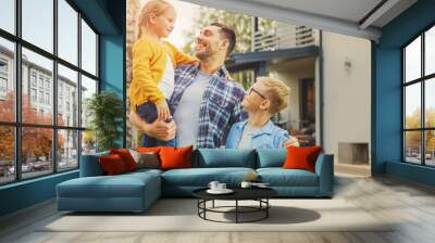 Portrait of a Happy Family of Three: Father, Daughter, Son. They Are Posing In Front of Camera on a Lawn Next to Their Country House. Dad is Holding the Girl in His Arms. Boy is Holding a Football. Wall mural