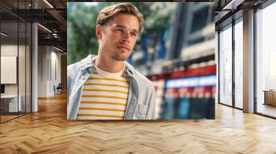 Portrait of a Happy Handsome Young Man in Casual Clothes Posing on the Street. Successful Male Model in Big City Living Urban Lifestyle. Background with Office Buildings and Billboards. Dutch Angle. Wall mural