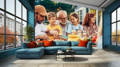 Portrait of a Happy Senior Grandfather Holding His Bright Talented Little Grandchildren on Lap at a Outdoors Dinner Party with Food and Drinks. Family Having a Picnic Together with Children. Wall mural