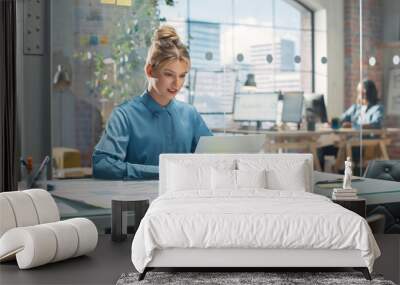 Portrait of Beautiful Caucasian Woman Working on Laptop Computer at a Bright Creative Office. Young Female Manager Updating Employees' Schedules and Answering Colleagues' E.mails Wall mural