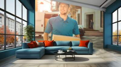 Portrait of Delivery Man Holds Cardboard Box Package Standing in Modern Stylish Business District with Delivery Van in Background. Smiling Courier On Way to Deliver Postal Parcel to Client. Sun Flare Wall mural