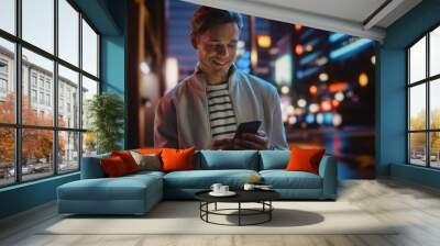 Portrait of Man Using Smartphone Walking Through Night City Street Full of Neon Light. Smiling Stylish Man Using Mobile Phone, Social Media, Online Shopping, Texting on Dating App. Wall mural