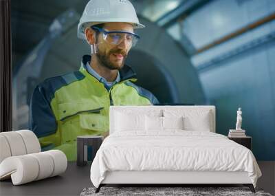 Portrait of Professional Heavy Industry Engineer / Worker Wearing Safety Uniform and Hard Hat Uses Tablet Computer. In the Background Construction Factory for Oil, Gas and Fuels Transport Pipeline Wall mural