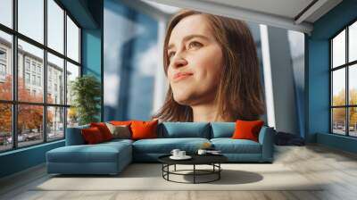 Portrait of Successful Businesswoman Riding Glass Elevator to Office in Modern Business Center. Young Beautiful Female Looking at Modern Downtown Skyscrapers Out of the Panorama Window in the Lift. Wall mural