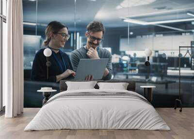 Portrait of Two Creative Young Female and Male Engineers Using Laptop Computer to Analyze and Discuss How to Proceed with the Artificial Intelligence Software. Standing in High Tech Research Office Wall mural