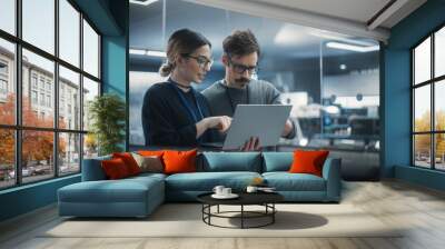 Portrait of Two Creative Young Female and Male Engineers Using Laptop Computer to Analyze and Discuss How to Proceed with the Artificial Intelligence Software. Standing in High Tech Research Office Wall mural