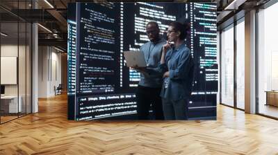 Portrait of Two Diverse Developers Using Laptop Computer, Discussing Lines of Code that Appear on Big Screens Surrounding Them. Male and Female Programmers Creating a Software Together, Fixing Bugs Wall mural