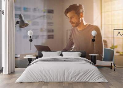 Professional Creative Man Sitting at His Desk in Home Office Studio Working on a Laptop, Concentrated Man Using Notebook Computer. Wall mural