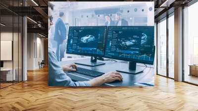 Professional Engineer Works on a Computer with a 3D CAD Software and Tests the Electric Car Chassis Prototype with Wheels, Batteries and Engine Standing in a High Tech Development Laboratory. Wall mural