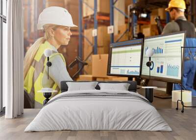 Professional Female Worker Wearing Hard Hat Uses Computer with Inventory Status Checking and Delivery Software in the Retail Warehouse full of Shelves with Goods. Delivery, Distribution Center  Wall mural