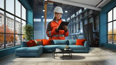 Professional Heavy Industry Engineer Worker Wearing Safety Uniform and Hard Hat, Using Tablet Computer. Serious Successful Female Industrial Specialist Walking in a Metal Manufacture Warehouse. Wall mural