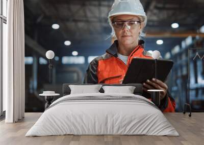 Professional Heavy Industry Engineer/Worker Wearing Safety Uniform and Hard Hat Uses Tablet Computer. Serious Successful Female Industrial Specialist Walking in a Metal Manufacture Warehouse. Wall mural