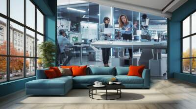 Professional Multicultural Team of Two Female Engineers Using Industrial Programmable Robotic Arm in a Factory Development Workshop. Robot Hand Machine Picking Up and Holding a Microchip. Wall mural