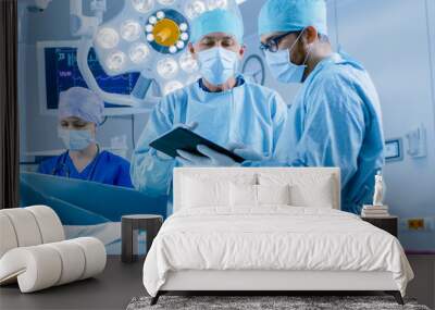 Professional Surgeons and Assistants Talk and  Use Digital Tablet Computer During Surgery. They Work in the Modern Hospital Operating Room. Wall mural