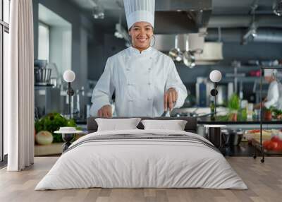 Restaurant Kitchen: Portrait of Black Female Chef in Action, Uses Pan to Cook Delicious, Traditional Authentic Food, Looks at Camera and Smiles. Healthy gourmet Dishes. Medium Wide Shot Wall mural