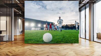 Shot of a Football Ball Lying on a Stadium Grass. Professional Soccer Player Outruns Members of Opposing Team and Ready to Kick the Ball to Score Goal. Wall mural