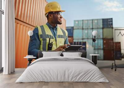 Smiling Portrait of a Handsome African American Black Industrial Engineer in Yellow Hard Hat and Safety Vest Working on Tablet Computer. Foreman or Supervisor in Container Terminal. Wall mural