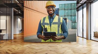 Smiling Portrait of a Handsome African American Black Industrial Engineer in Yellow Hard Hat and Safety Vest Working on Tablet Computer. Foreman or Supervisor in Container Terminal. Wall mural