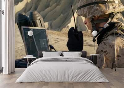 Soldier is Using Laptop Computer for Tracking the Target and Radio for Communication During Military Operation in the Desert Wall mural