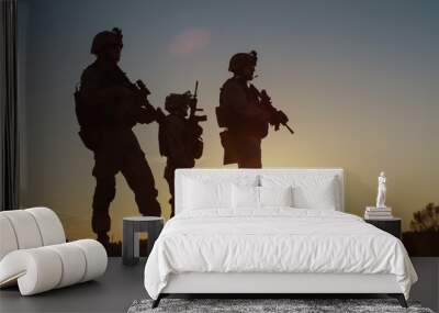 Squad of Three Fully Equipped and Armed Soldiers Standing on Hill in Desert Environment in Sunset Light. Wall mural