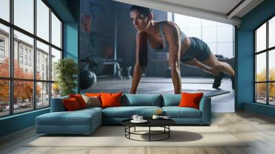 Strong and Fit Athletic Woman in Sport Top and Shorts is Doing Push Up Exercises in a Loft Style Industrial Gym with Motivational Posters. It's Part of Her Cross Fitness Training Workout.  Wall mural